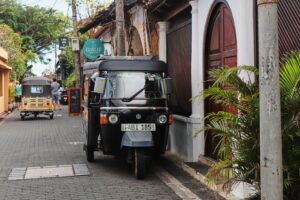 A black tuk-tuk parked along a cobblestone street with colonial buildings in historic Galle Fort, Sri Lanka.