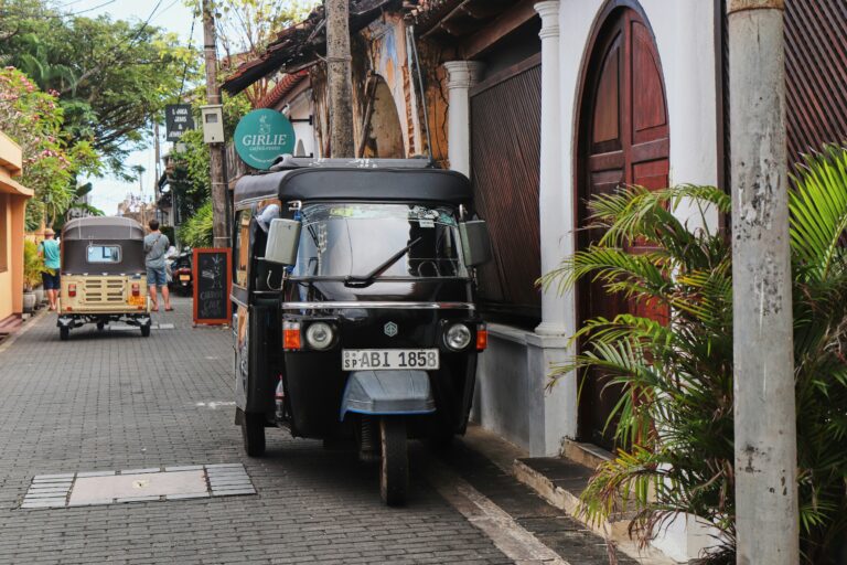 A black tuk-tuk parked along a cobblestone street with colonial buildings in historic Galle Fort, Sri Lanka.